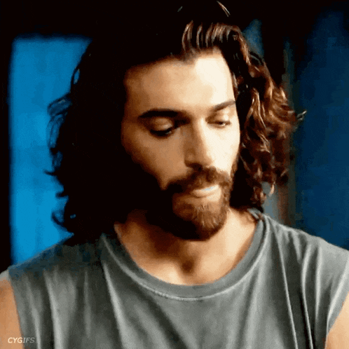 a man with long hair and a beard is wearing a sleeveless t-shirt .