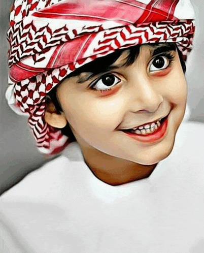 a young boy wearing a red and white head scarf is smiling for the camera .