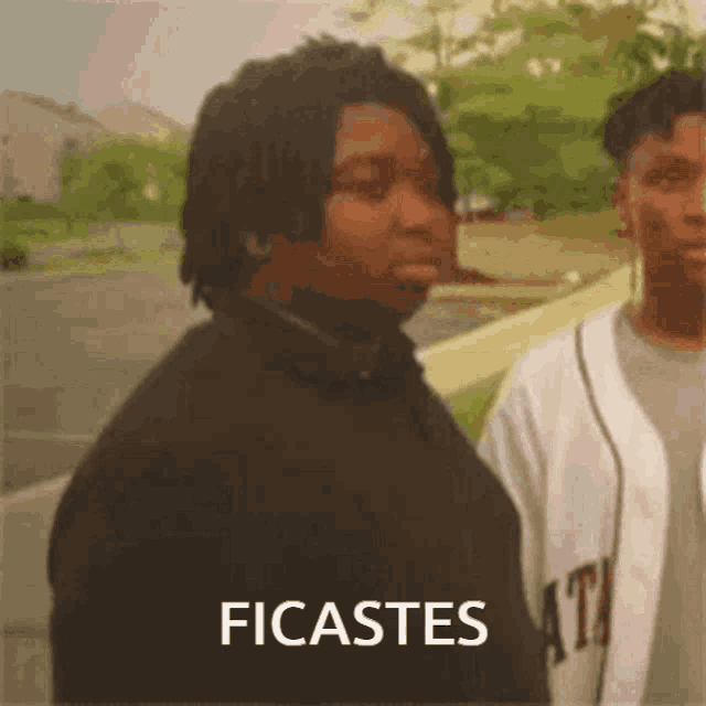 a man in a black jacket is standing next to a man in a white jersey with the word ficastes on the bottom