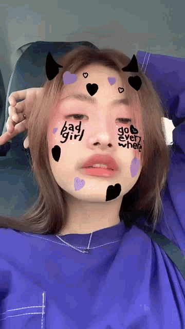 a girl with bad girl written on her face is wearing a blue shirt