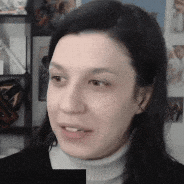 a close up of a woman 's face with a picture of a man on the wall behind her
