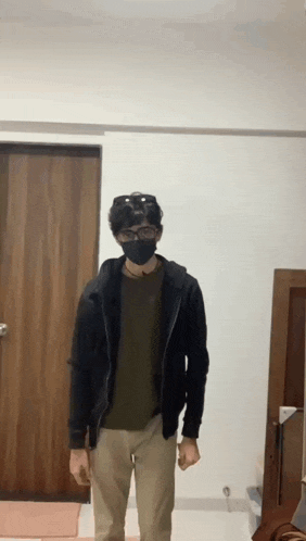 a man wearing a face mask and sunglasses is standing in front of a door .