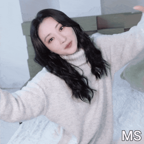 a woman in a white sweater is taking a selfie with the letters ms below her