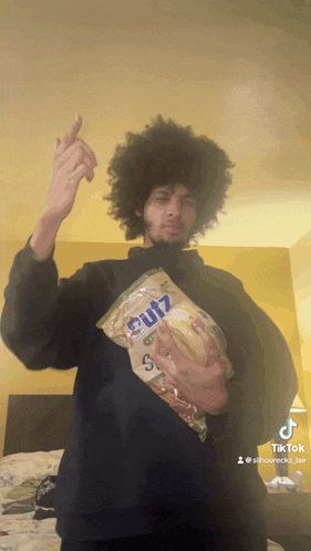 a man is holding a bag of cutz chips and giving a middle finger