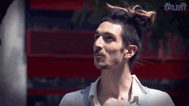 a man with a bun on his head is standing in front of a sign that says talent on it
