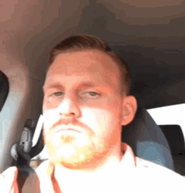 a man with a beard is sitting in a car and looking at the camera