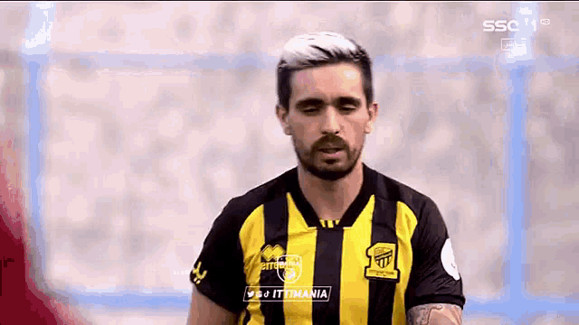 a man with a beard is wearing a yellow and black striped jersey .
