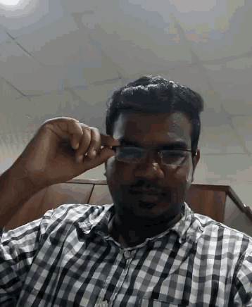 a man wearing glasses and a plaid shirt looks at the camera