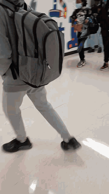 a person wearing a backpack is walking down a hallway