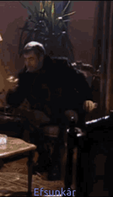 a man sits in a chair with the word efsunkar on the bottom right