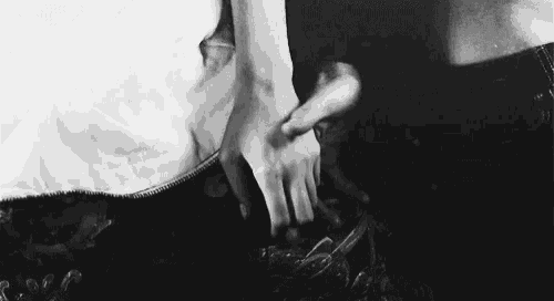 a black and white photo of a person 's hands on another person 's pants .