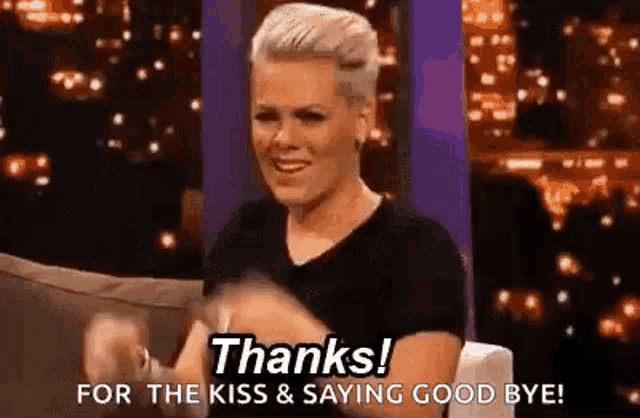 a woman is sitting on a couch with her hands in the air and saying `` thanks for the kiss and saying good bye ! ''