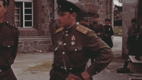 a man in a green uniform holds a camera