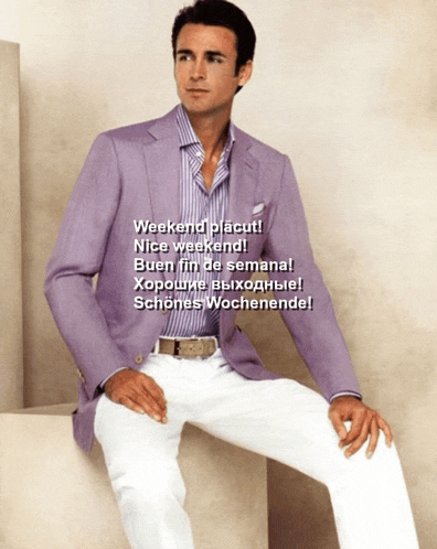 a man wearing a purple jacket and white pants sits on a cube