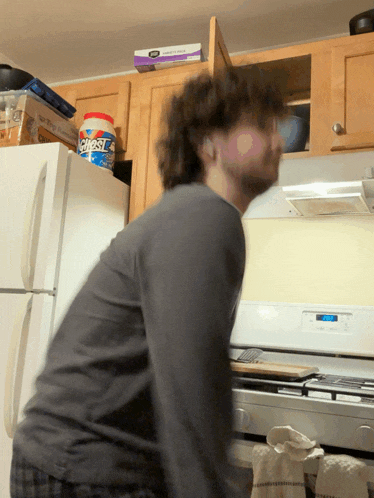 a man standing in front of a stove with a can of chestnuts on top of the refrigerator