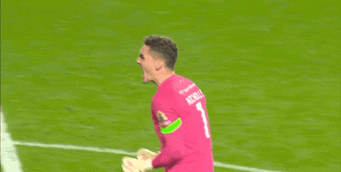 a soccer player in a pink jersey is screaming on the field .