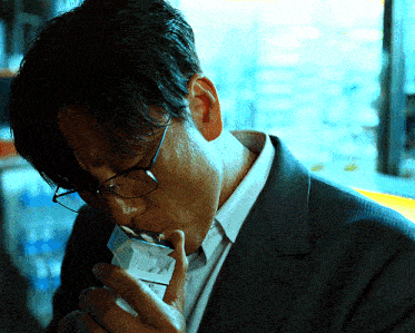 a man wearing glasses and a suit is holding a piece of paper in his hand