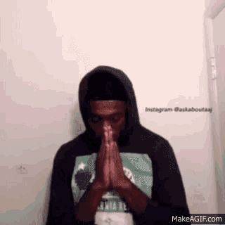 a man in a hoodie is praying with his hands folded in front of him .
