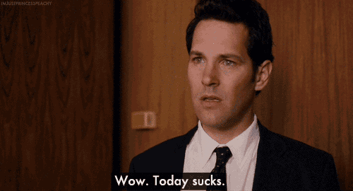 a man in a suit says wow today sucks in front of a wooden wall