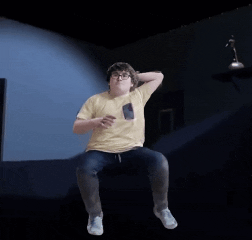 a boy in a yellow shirt is jumping in the air with his arms outstretched