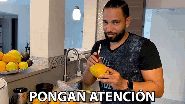 a man is holding a mango in front of a sign that says ' ongan atencion '