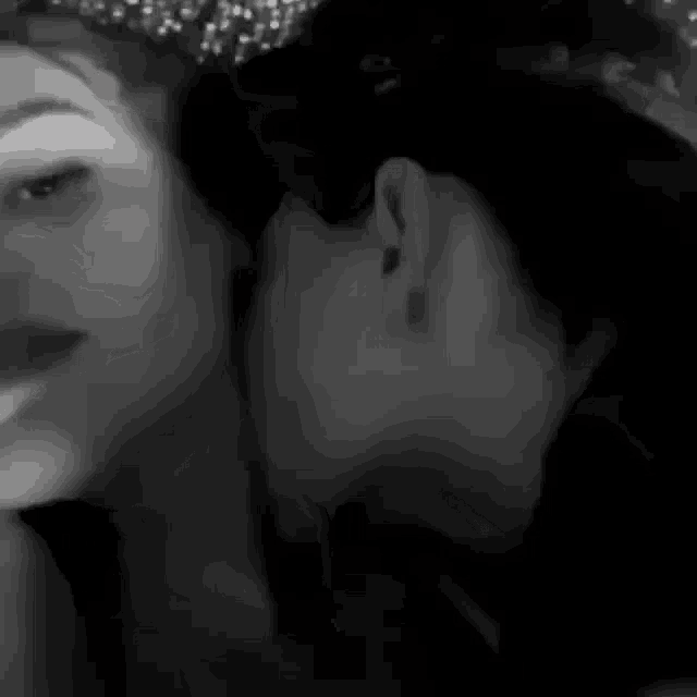 a man whispering into a woman 's ear in black and white