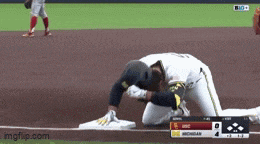 a baseball player is kneeling on the base while another player looks on