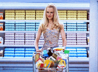 a woman is pushing a shopping cart full of groceries including a bag of maggi