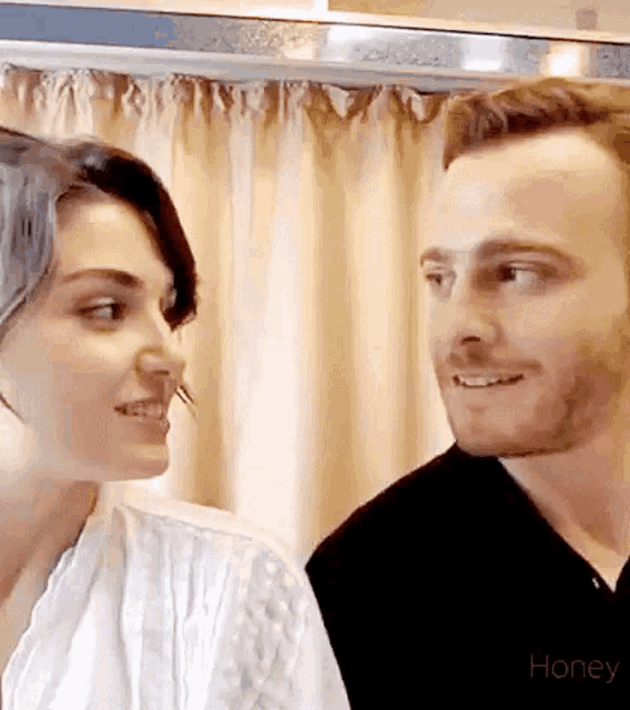 a man and a woman are looking into each other 's eyes and smiling .