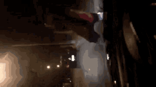 a person in a red jacket is walking down a street at night