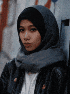 a woman wearing a hijab and a black jacket with the letter l on the sleeve