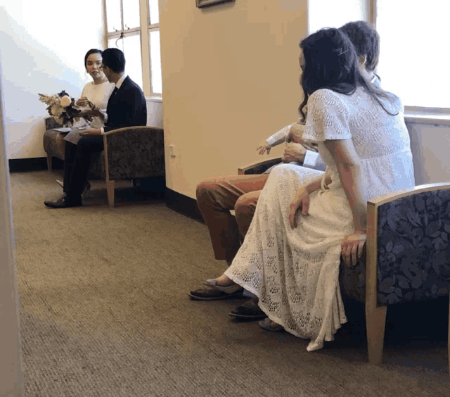 a woman in a white dress sits next to a man