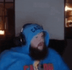 a man with a beard is wearing a blue hoodie and headphones