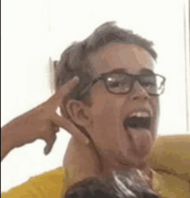 a woman wearing glasses is sticking her tongue out while sitting on a couch .