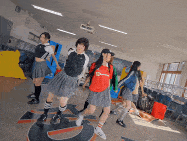 a group of girls are dancing in a classroom and one of them is wearing a shirt that says ' adidas ' on it