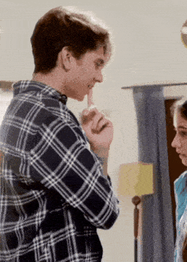 a man in a plaid shirt covering his mouth with his hand