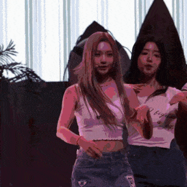 two women are dancing in front of a surfboard and one has a shirt that says " i began "