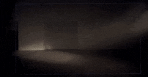a dark room with a door and a light coming through it