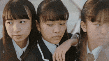 three girls are standing next to each other and one has her arm on the other 's shoulder