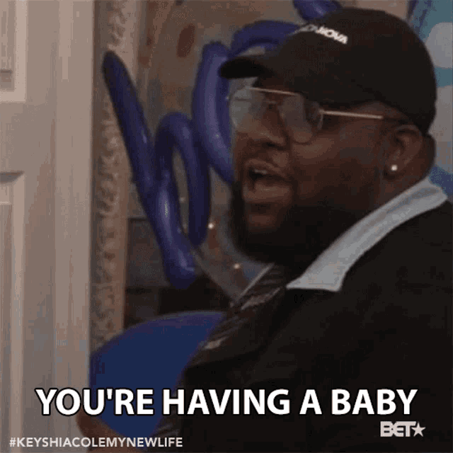 a man wearing a hat and glasses says " you 're having a baby "