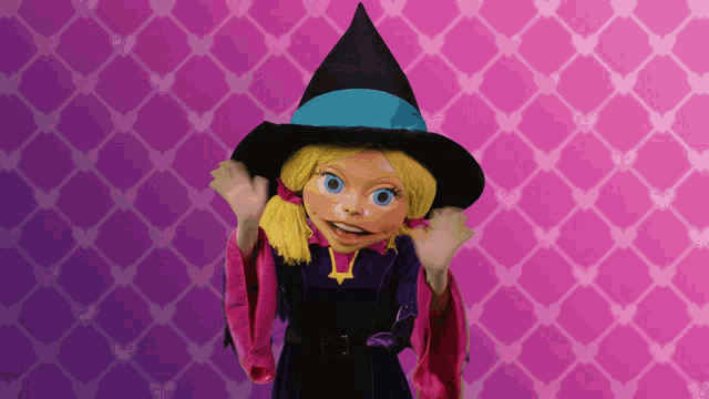 a doll in a witch costume is standing in front of a pink and purple background