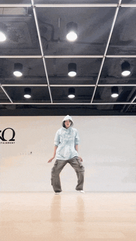 a man in a hoodie is dancing in front of a sign that says ω
