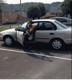a shirtless man is getting out of a white car in a parking lot