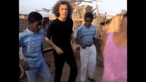 a group of people are standing next to each other dancing in a field .