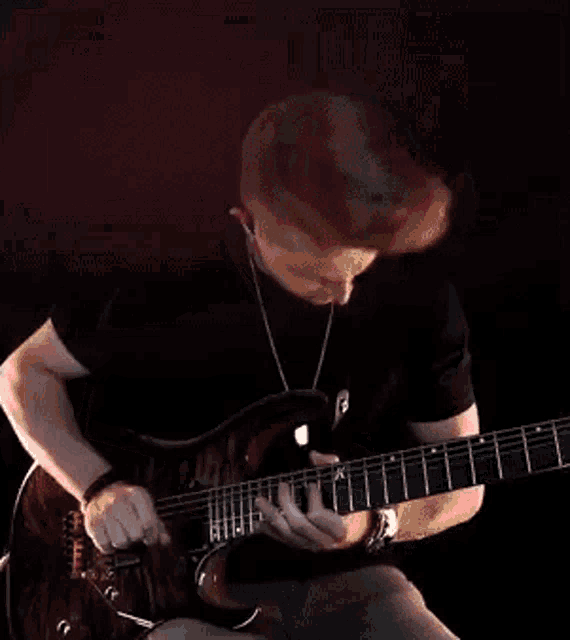 a man in a black shirt is playing a guitar in front of a red background