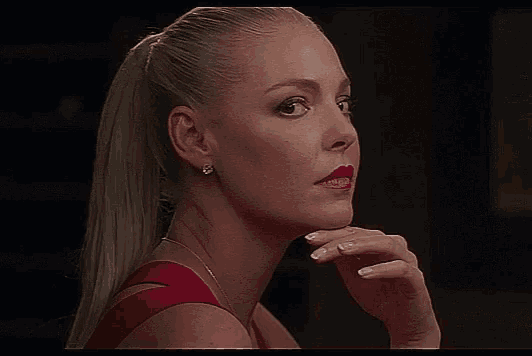 a woman in a red dress has her hand on her face