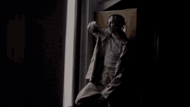 a person sitting in a dark room with a sign on the wall that says ' a '