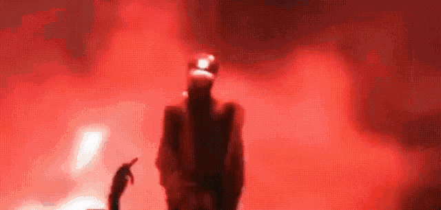 a blurry picture of a person standing in a dark room with a red background