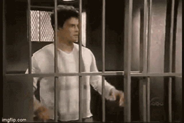 a man is behind bars in a jail cell .