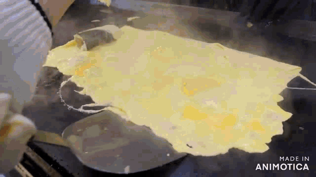 a person is cooking eggs on a griddle with a spatula and the words made in animotica on the bottom